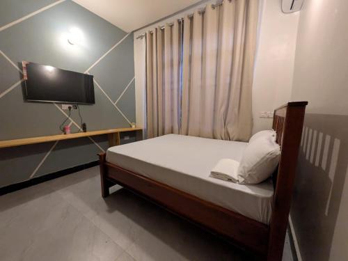 a small bedroom with a bed and a tv at Nyumbani Executive Lodge in Ilala