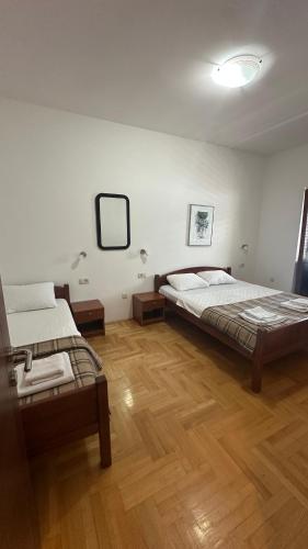 a bedroom with two beds and a wooden floor at Apartmani Cebra & Lisa in Topla