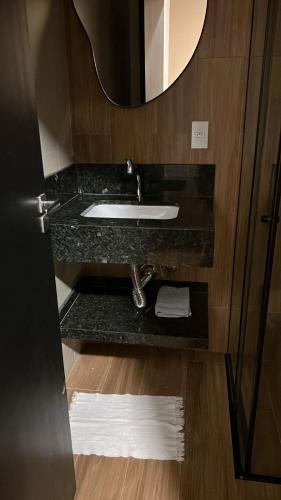 a bathroom with a sink and a mirror at Carrijo Hotel in Marília