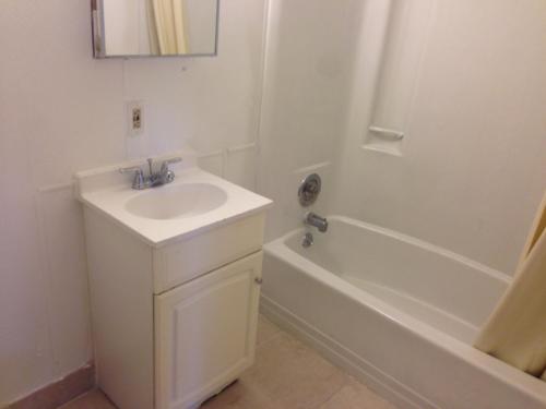 a white bathroom with a sink and a bath tub at Cloud 9 Inn - Beach Hotel in Seaside Heights