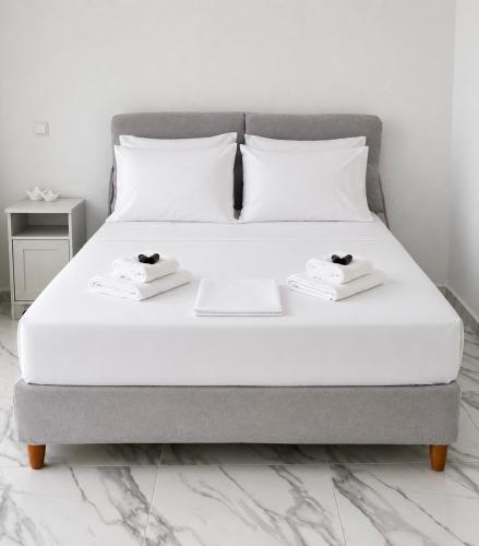 una cama blanca con dos toallas blancas encima en Dear John, en Hydra