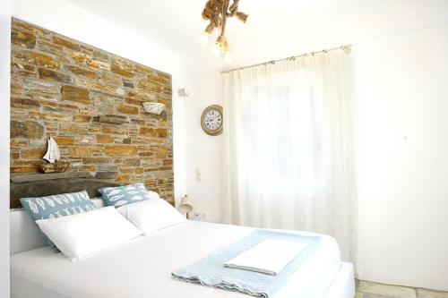 a bedroom with a white bed and a brick wall at Utopia Kythnos Althea in Kithnos