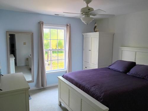 a bedroom with a purple bed and a window at Beach Hoppers' Hideaway in Cape Charles