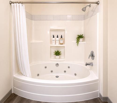 a white bathroom with a tub and a shower at Ace Inn in Fort McMurray