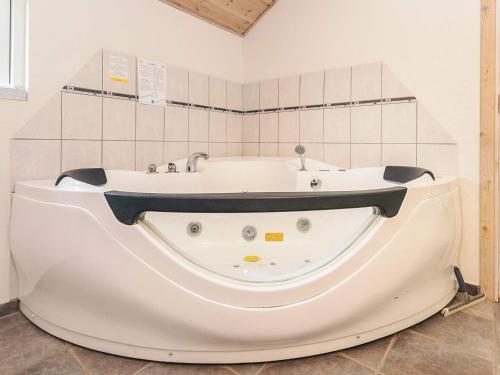 a white bath tub in a bathroom with a tile wall at 12 person holiday home in Idestrup-By Traum in Bøtø By