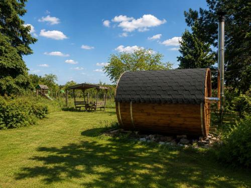 a small wooden shed with a black roof in a field at Ferienhaus Schorfheide Kamin Sauna Naturgarten nahe Seen & Wildpark in Schorfheide
