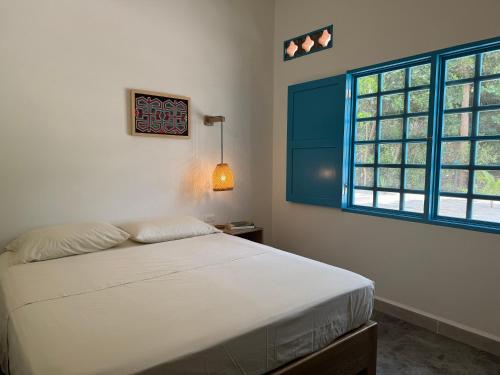 a bedroom with a white bed and two windows at Donde Andres en la Playa in Necoclí