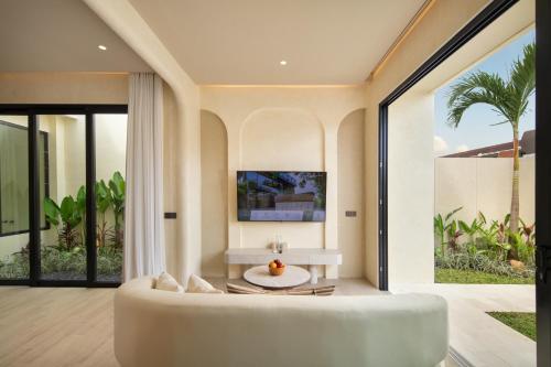 a living room with a white couch and a table at The Lario Collection - A Wellness Resort in Seminyak