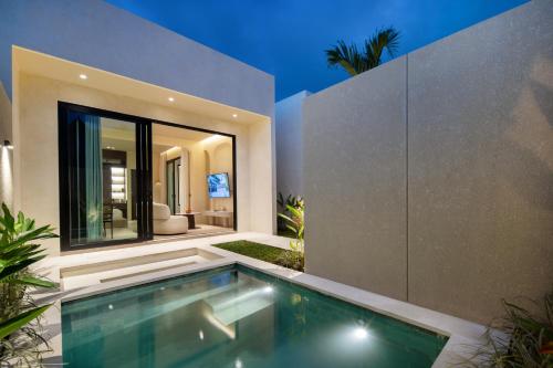 a swimming pool in front of a house at The Lario Collection - A Wellness Resort in Seminyak