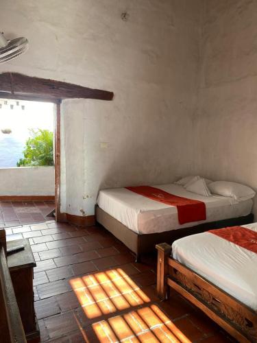 two beds in a room with a window at Hotel Casa Posada Don Chepe in San Gil