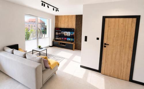 a living room with a white couch and a wooden door at Apartament Niebo przy plaży ROYAL APARTS OSTRÓDA in Ostróda