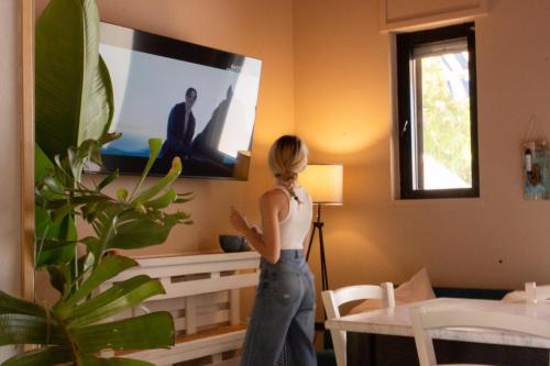 a woman standing in a living room watching a tv at Villa Panoramica Sunset House in Torre Vado