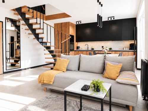 a living room with a couch and a staircase at Apartament Niebo przy plaży ROYAL APARTS OSTRÓDA in Ostróda