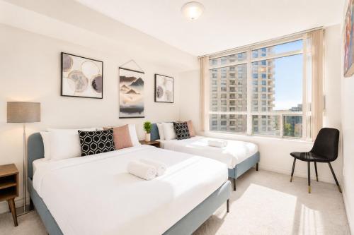 a bedroom with two beds and a desk and a window at High-End 2BR 2BATH Condo-Steps to Square One Mall in Mississauga