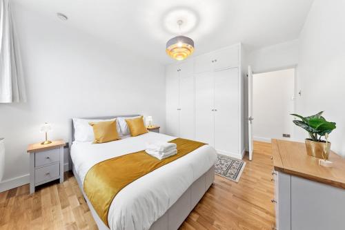 a white bedroom with a large bed and a desk at Modern 2 Bed Flat 5 mins Ealing Broadway Station in Ealing