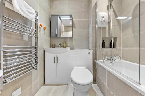 a bathroom with a toilet and a sink and a tub at Modern 2 Bed Flat 5 mins Ealing Broadway Station in Ealing