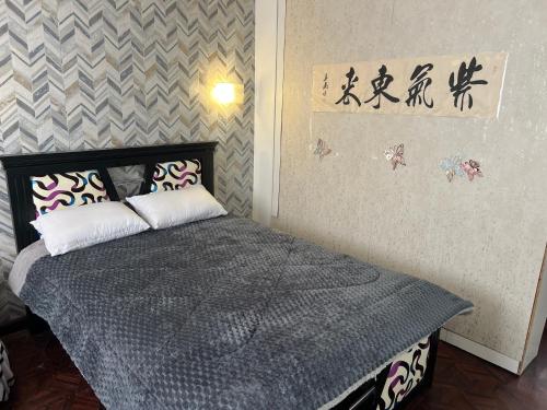 a bedroom with a bed with a gray comforter at Suite Acogedora Centro de Tulcán in Tulcán