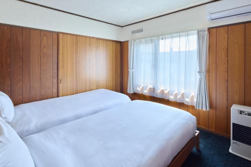 a bedroom with two beds and a window at Furano Lavender House helps guests book great restaurants in Furano in Furano