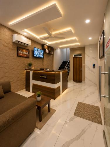 a lobby with a couch and a tv on a wall at Hotel Golden Glory Scheme 103 in Indore