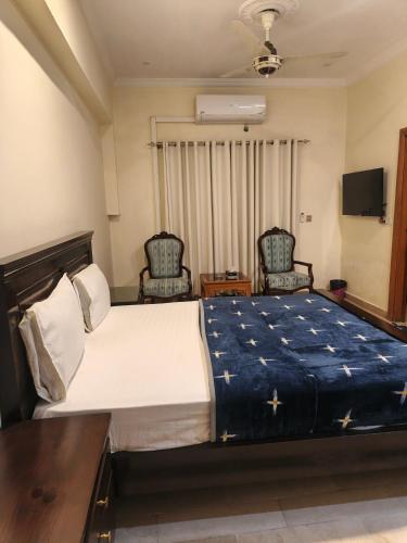 a bedroom with a large bed and two chairs at Timber Box Hostels in Rawalpindi