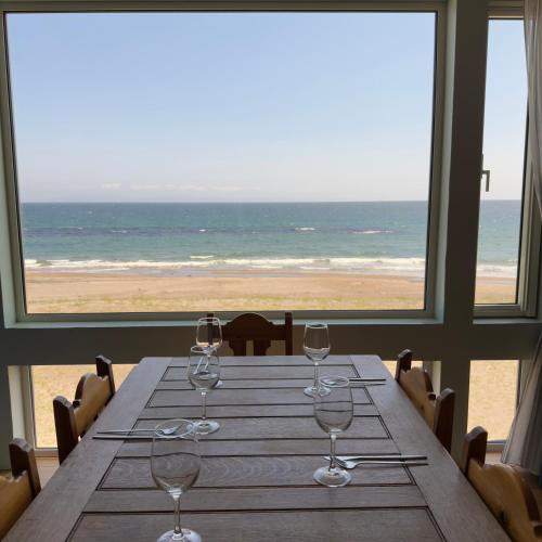 a table with wine glasses and a view of the beach at Seaside Inn KOKOMO in Hakodate