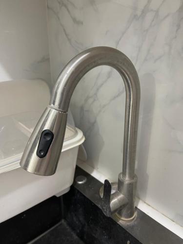 a metal faucet next to a toilet in a bathroom at MANEL Guest House - Donsol, Philippines in Donsol