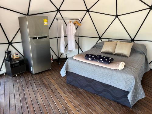 a bedroom with a bed and a refrigerator in a room at Glamping oriente antioqueño in San Vicente