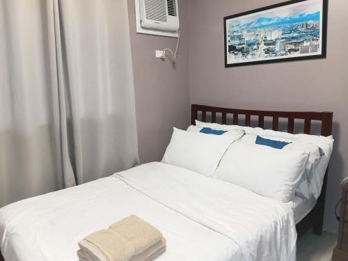 a bed with white sheets and a towel on it at Amaia Steps Condominium Studio -across Ayala Mall Capitol Central in Bacolod