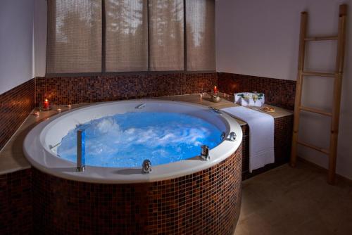 a bathroom with a jacuzzi tub with blue water at Mercure Bale Mulhouse Aeroport in Blotzheim
