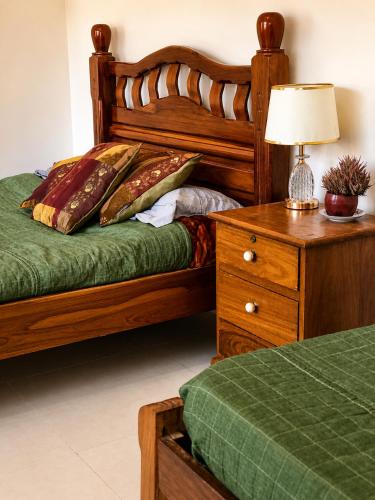 a bedroom with a bed and a dresser with a lamp at Looking Samaipata Habitación Doble in Samaipata