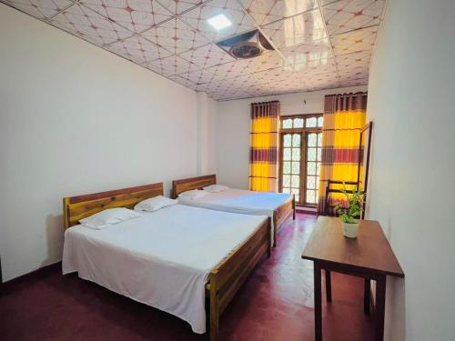 a bedroom with two beds and a table in it at River Park Holiday Home in Badulla