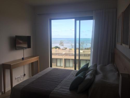 a bedroom with a bed and a large window at Azuri Appartements De Luxe in Roches Noires