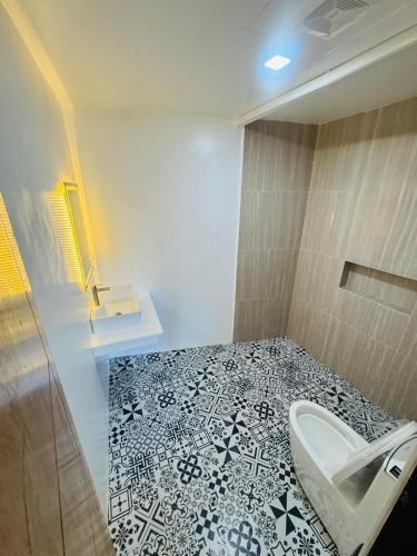 a bathroom with a toilet and a black and white tile floor at Villa Luyo in General Luna