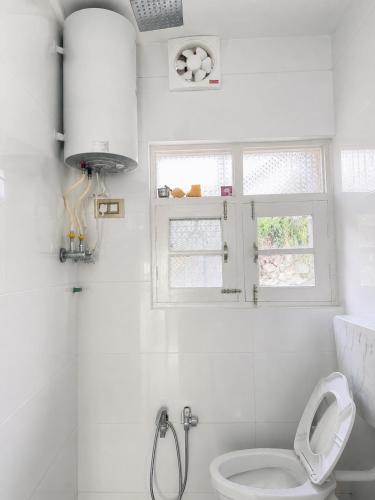 a white bathroom with a toilet and a window at Everest Guest House in Gulmarg