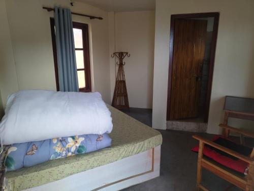 a bedroom with a bed and a window and a door at Balthali Heritage Inn Resort in Panaoti