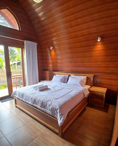 a bed in a room with a wooden wall at Bale Rinjani Lodge & Cafe in Tetebatu
