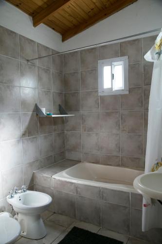 a bathroom with a tub and a toilet and a sink at El Solar in Vuelta de Obligado