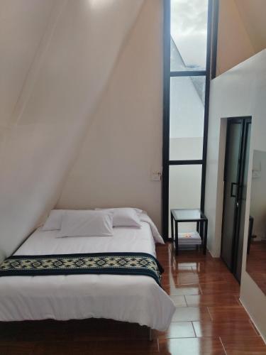 a bedroom with a bed and a large window at Tungurahua Eco Lodge INN BAÑOS in Quillullaco