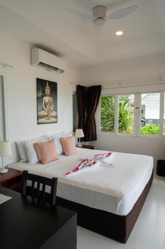 a bedroom with a large white bed with pink pillows at The Cosy Maenam Beach Resort in Mae Nam