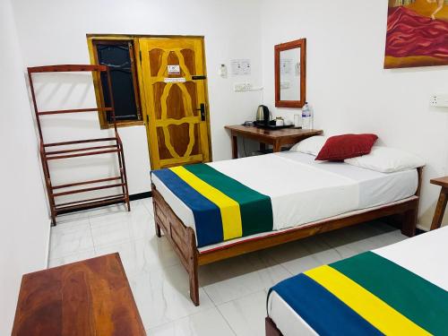 a bedroom with two beds and a desk and a ladder at Ratnam Hotel Jaffna in Jaffna