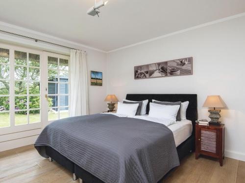 a bedroom with a bed with white walls and windows at Leuchtturmblick-Sued in Kampen