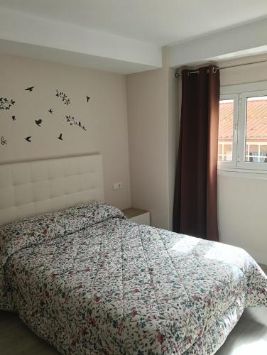a bedroom with a bed with birds on the wall at Piso Gallega in Finisterre
