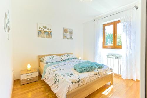 a white bedroom with a bed and a window at Family Villa Krizanci Istria in Žminj