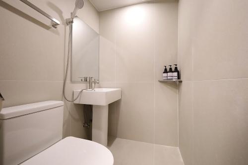 a white bathroom with a toilet and a sink at Hotel Soonsu Mia in Seoul