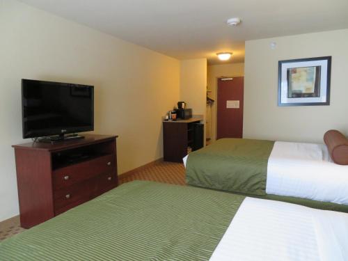 a hotel room with two beds and a flat screen tv at Cobblestone Inn & Suites - Rugby in Rugby