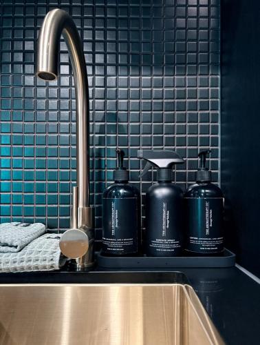 a kitchen sink with two bottles on a counter at Green Rooms Braddon - Designer Micro Apartments in Braddon