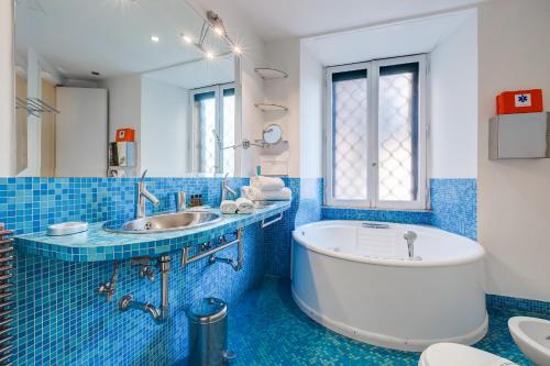 ローマにあるHoliday House Belle Arti - NEL CUORE DI ROMAの青いタイル張りのバスルーム(バスタブ、シンク付)