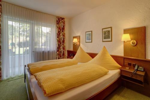 a bedroom with two beds with yellow sheets and a window at Pension Bergstub`n in Saldenburg