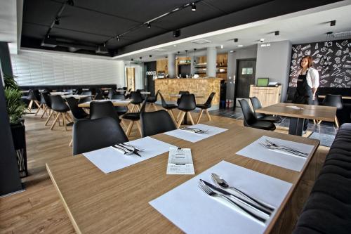 a restaurant with tables and chairs and silverware at Hotel Viktória in Sárvár
