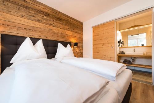 a bedroom with a large white bed with a wooden wall at APART Forellenhof in Flachau